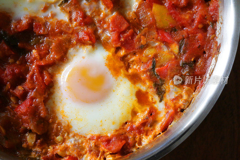 这是地中海健康早餐shakshouka / shakshuka / chakchouka的特写图片，用番茄、辣椒、洋葱、橄榄油和大蒜酱煮熟的鸡蛋
